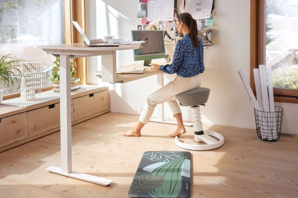 Dein ergonomischer Arbeitsplatzl Bild zeigt ein Frau an einem höhenverstellbaren Arbeitsplatz, Link führt zu einem Blogbeitrag zum Thema "Ergonomischer Arbeitsplatz"