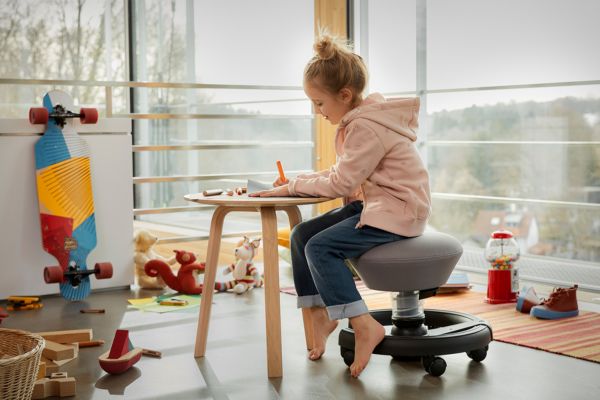 Einrichtung m Kinderzimmer Kind am Tisch malt und sitzt auf Swoppster. Link führt zu einem Blogbeitrag zum Thema Einrichtung im Kinderzimmer