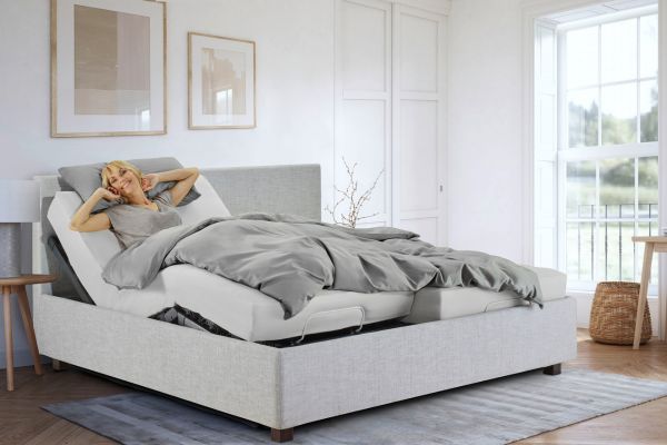 In kleinen Zimmern sollte das Bettsystem den Rücken gut unterstützen und wenig Platz verbrauchen. Link führt auf eine Seite mit ergonomischen Bettsystemen. Bild zeigt eine Frau in einem Doppelbett.