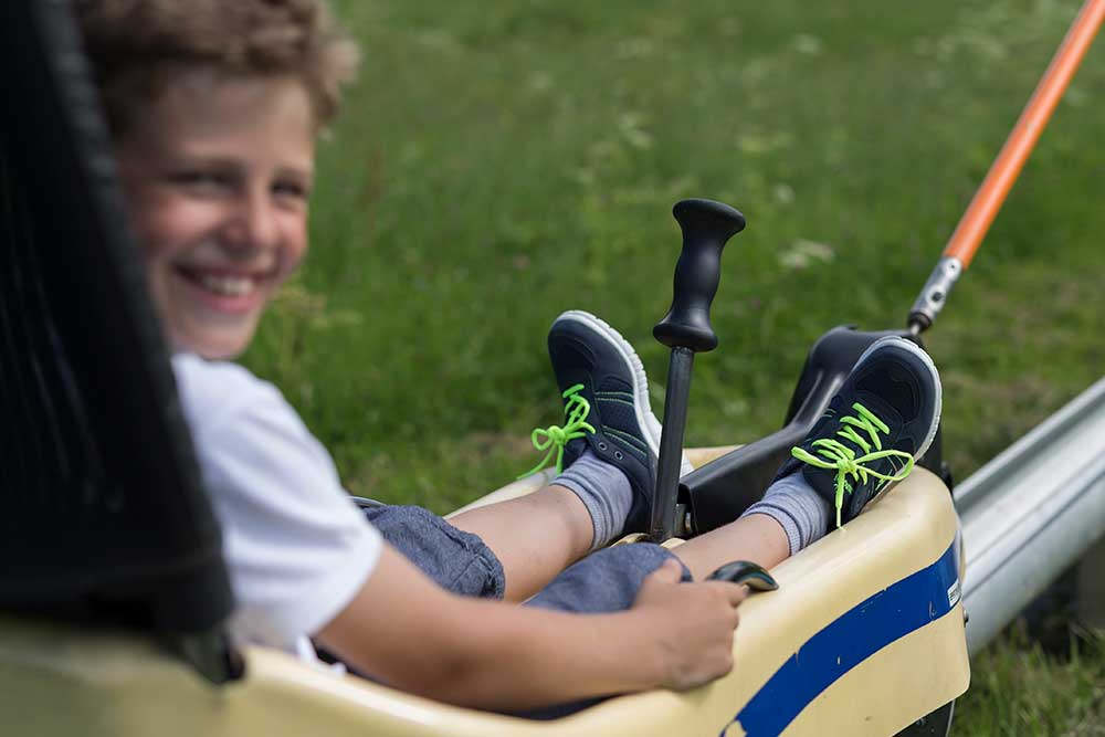 Kinderschuhe Junge sitzt auf Gefährt. Link zu Kinderschuhe