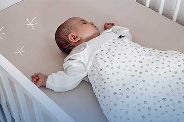 aktion-gesunder-ruecken-gepruefte-produkte-autokindersitze-babyschalen schöafendes Baby in Schlafsack im Kinderbett. Link zu Babymatratzen