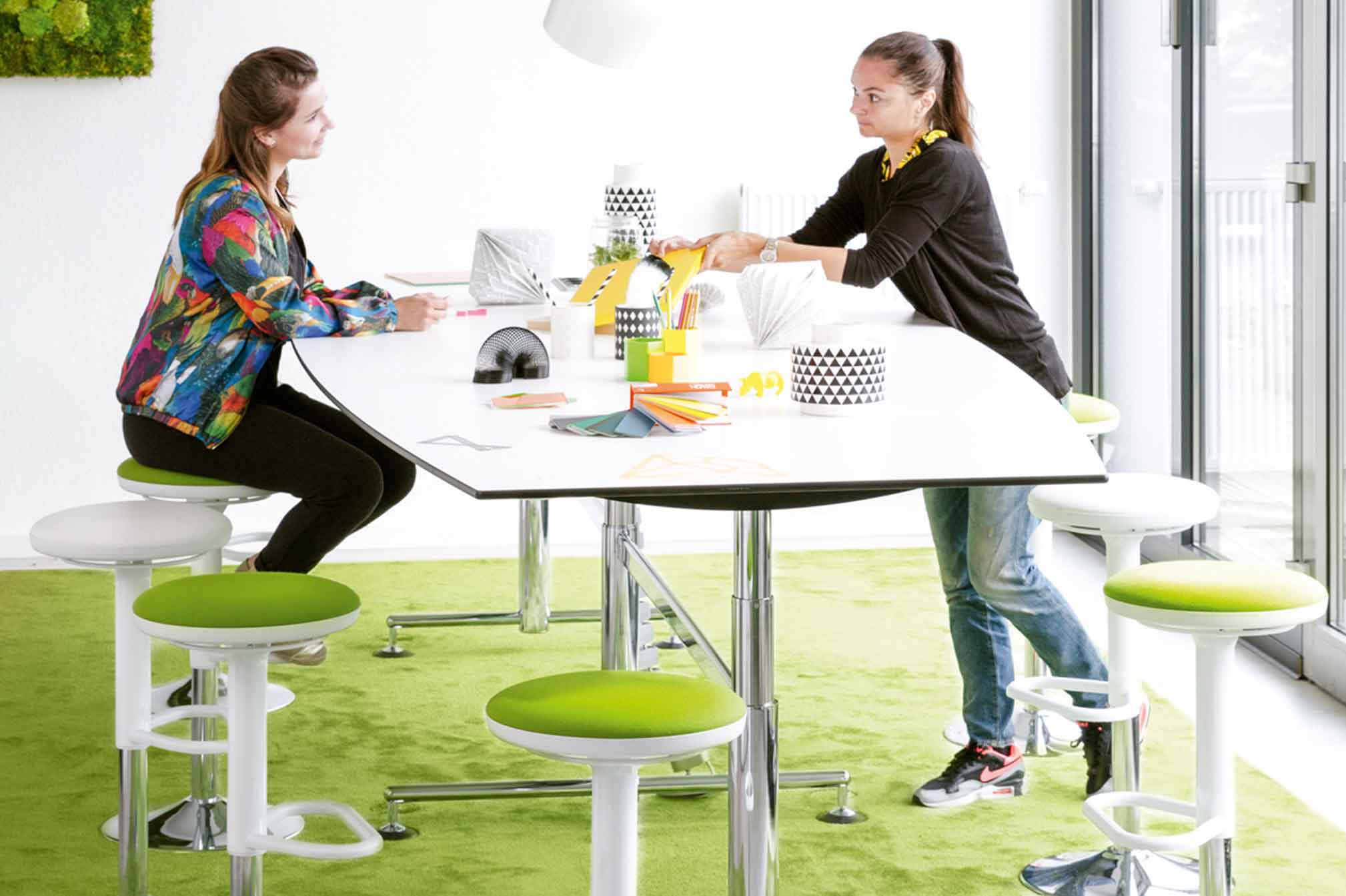 zwei Frauen an einem großen Tisch bereiten ein Meeting vor